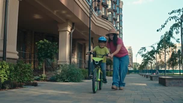 一位母亲教她的儿子骑自行车 父母帮助孩子在城市里玩耍 一起笑 高质量的4K镜头 — 图库视频影像