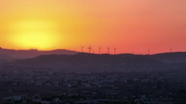 Sürdürülebilir Geleceğe Bir Bakış: Sunset 'teki Görkemli Dağ Manzarasında Rüzgar Türbinleri. Yüksek kalite 4k görüntü