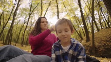 Autumns Kucaklıyor: Bir Anne, Altın Yapraklar Arasında Piknik yaparken Parlıyor. Yüksek kalite 4k görüntü