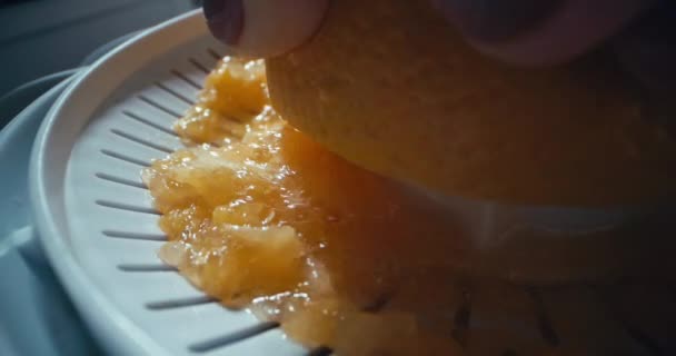 ジューサーでオレンジからジュースを絞るマクロスローモーションビデオ 朝食のためにキッチンで自宅で新鮮な柑橘類ジュース 高品質の4K映像 — ストック動画