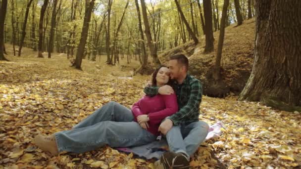 秋の森でピクニックに恋するカップル 男は長い葉の季節の散歩で女性を抱き キスします 高品質の4K映像 — ストック動画