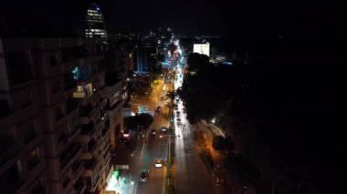 Gece Limasol 'un şehir manzarasının havadan görüntüsü. Rüzgarlı bir mevsimde bir tatil köyünde sokak lambaları ve araba farları yolda. Yüksek kalite 4k görüntü