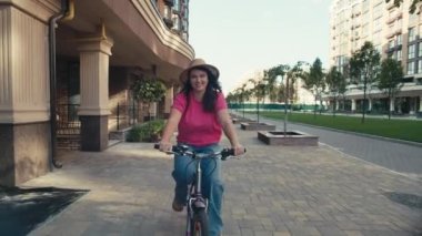 Bir kadın şehir sokaklarında bisiklet sürüyor. Aktif yaşam tarzı, kızlar için spor, gülümseme ve eğlence. Yüksek kalite 4k görüntü