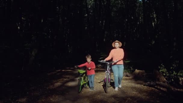 母亲和儿子在夏天的森林里骑自行车散步 积极的家庭娱乐在自然界中 高质量的4K镜头 — 图库视频影像
