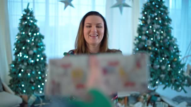 クリスマスプレゼントを受け取った白人女性の肖像画 幸せな笑顔の少女は クリスマスツリーの近くの箱に満足しています 高品質の4K映像 — ストック動画