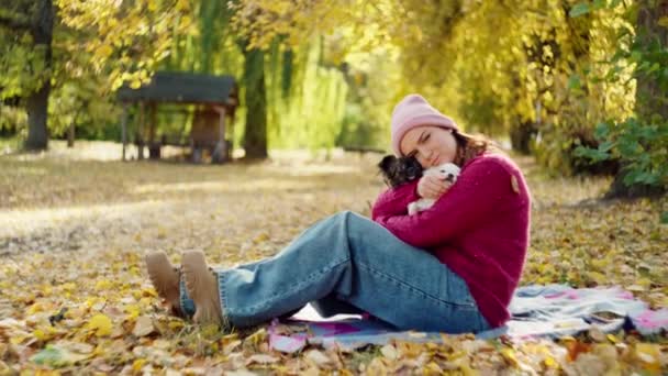 愛と自然の交響曲 美しい少女テンダーリーは犬を抱き 黄色い葉で輝く秋の日にボンドを育てます 高品質の4K映像 — ストック動画