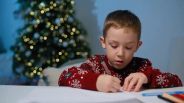 Büyülü Anlar: Çocuk Noel Baba 'ya Evde Mektup Yazıyor, Noel Ağacı Altında Heyecan Büyüyor. Yüksek kalite 4k görüntü