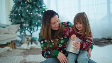 Kız ve anne Noel ağacının altında Noel Baba 'dan bir hediye açıyor. Evde yeni yılın kutlu olsun atomosfer çocuk. Yüksek kalite 4k görüntü