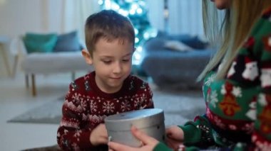 Anne ve oğul bir Noel hediyesi açın. Noel ağacının yanında mutlu bir çocuk yeni yıl tatilinde sevinir. Şaşırtma ve mutluluk duyguları. Yüksek kalite 4k görüntü