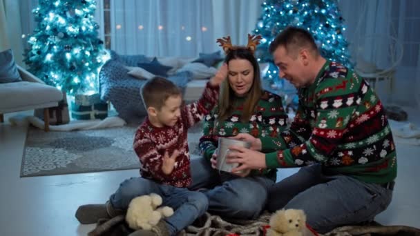 爸爸和儿子打开圣诞老人的圣诞礼物 一家人坐在圣诞树旁 为这些惊喜 微笑和奇迹而欢欣鼓舞 高质量的4K镜头 — 图库视频影像
