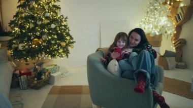 Cozy Family Time: Mother and Daughter Conding, Smartphone 'da Noel Animasyonunun Tadını Çıkartıyor, Eve Bayram Neşe Veriyor. Yüksek kalite 4k görüntü