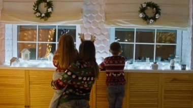 Şenlikli Sürprizler: Çocuklar Noel Baba 'nın Gelmesini Bekliyor, Annemle Pencere' ye Gelen Hediyeler Olarak Bakıyorlar. Yüksek kalite 4k görüntü