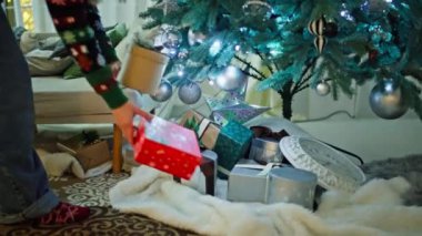 Noel ağacının altına hediye koyan bir kadının yakın çekimi. Noel arifesinde Noel Baba 'dan hediyelerle dolu kutular ve Noel atmosferi. Yüksek kalite 4k görüntü