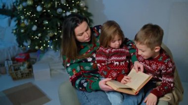 Sihirli Hikaye Zamanı: Anne ve Çocuklar Noel Masallarına Batmış, Dekoratif Ağaç Tarafından Kutlanan Ruh 'u kucaklıyorlar. Yüksek kalite 4k görüntü