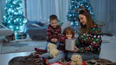 Sihirli Noel Boksu: Gülen Anne ve Çocuklar Ağacın orada Tatil Kutuları Açıyor, Noel Baba Büyüleyici Anlar, Çocuk Zevki ve Neşeli Neşe. Yüksek kalite 4k görüntü