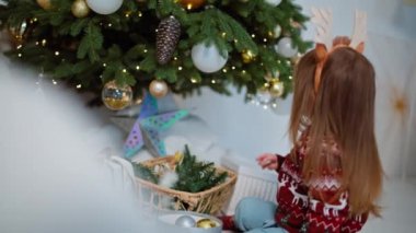 Dekoratif Neşe: Neşeli Çocuk Noel Ağacı 'nı Güzelleştiriyor, Noel Baba' yı Beklerken Neşeli Atmosfer Oluşturuyor. Yüksek kalite 4k görüntü