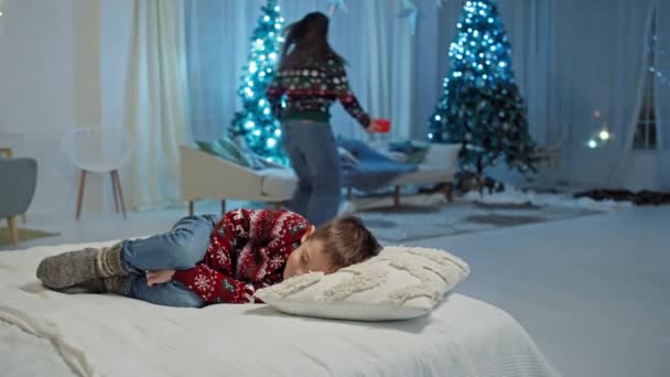 男孩睡觉时 妈妈把礼品盒放在树下 快乐的童年和等待圣诞老人的礼物 高质量的4K镜头 — 图库视频影像