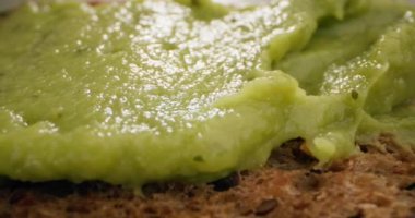 Makro yavaş çekim video guacamole sandviç üzerinde. Mutfakta avokado puanı pişiriyorum. Yüksek kalite 4k görüntü