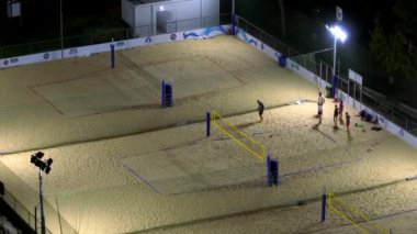 Alacakaranlık titreşimleri: Şehir manzaralarının hava keşfi ve Akşam Işıkları Altında Kum Voleybolu Keyifleri. Yüksek kalite 4k görüntü