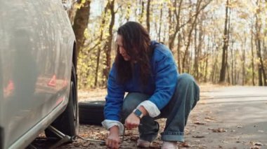 Otomotiv Çilesi Açıklandı: Kararlı Bir Kızın Araba Sorunlarını Yönetmesinin Hayal Kırıklığı ve Zaferi Büyüleyici Ormanda Bir Lastik Değişikliği Yapıyor. Yüksek kalite 4k görüntü
