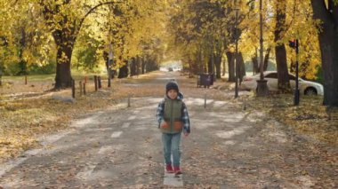 A happy schoolboy with a backpack goes to school on a yellow letter. Autumn is the time of study, the child rushes to classes. High quality 4k footage