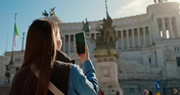 賑やかな街路で 女性は建物 雲の景色を背景に彼女の携帯電話上の像のイメージをキャプチャします — ストック動画