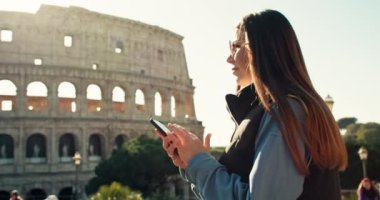 Bir kadın telefonundaki haritaya bakar ve Roma 'da Kolezyum' un yakınında yürür. Bir kız turist hafta sonu eski bir Avrupa şehrinde seyahat ediyor. Yüksek kalite 4k görüntü