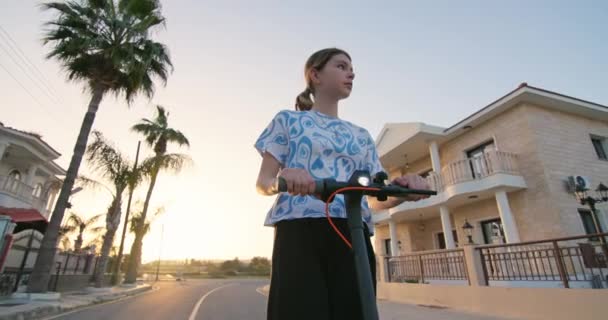 Ein Mädchen Teenageralter Fährt Bei Sonnenuntergang Mit Einem Elektroroller Auf — Stockvideo