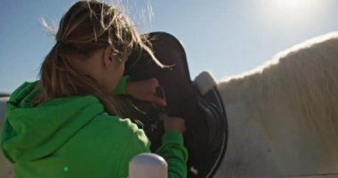Çiftlik Aşkı: Kadın Sadling ve Bridling Beyaz Atı, At Bakımı ve Binicilik Hazırlığı. Yüksek kalite 4k görüntü