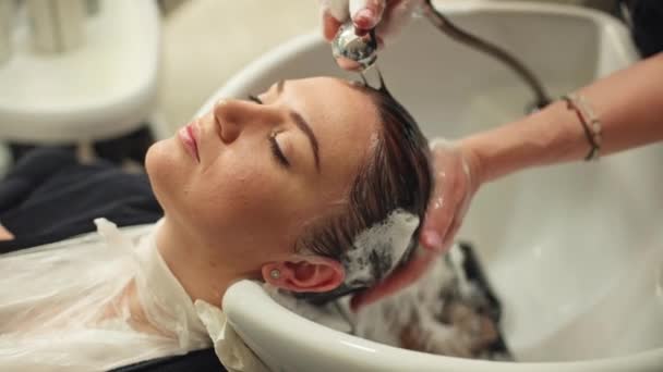 女性美容師は スタイリングとカラーリングの前に髪を洗い 美容サロンで美容手順を準備し クライアントサービスと女性の美容ライフスタイルでケアプロフェッショナリズムを強調します — ストック動画