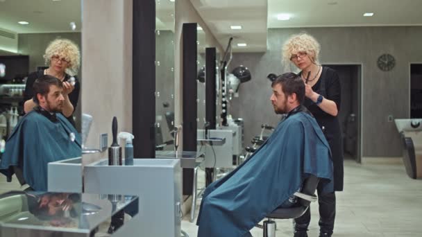 女性の美容師がハサミで大人の髪を切っています 美容室でのプロの仕事 ヘアケアのスタッフ 高品質の4K映像 — ストック動画