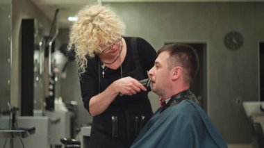 Bir kadın kuaför, bir adamın sakalını güzellik salonunda çıplak tıraş eder. Yüksek kalite 4k görüntü