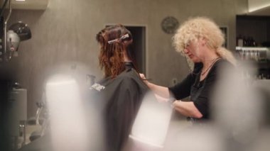 Bir kadın kuaför bir müşteri için saç tıraşı yapar. Stüdyoların profesyonel salonunda güzellik prosedürleri. Yüksek kalite 4k görüntü