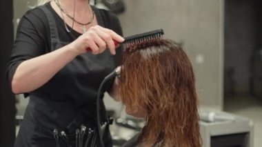 Bir kuaför tarakla bir kadının saçını tarar ve saç stili yapar. Güzellik kuralları bir güzellik stüdyosunda saç kesimi. Yüksek kalite 4k görüntü