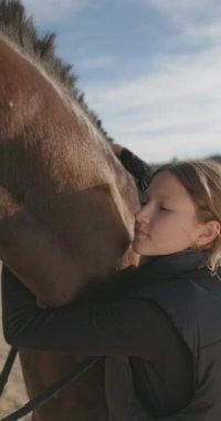 Bir kız çiftlikte bir ata sarılıp okşuyor. Hayvanlar için sevgi ve ilgi, ata binmeyi öğrenmek. Yüksek kalite 4k görüntü