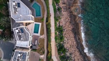 Seaside Splendor: Kıbrıs Rum Kesimi 'nin Paphos kentindeki Akdeniz kıyılarında havuzları olan çağdaş villaların havadan görünüşü. Yüksek kalite 4k görüntü