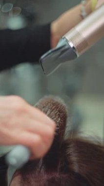 Bir kuaför, saç kurutma makinesi ve fırça yardımıyla bir kadın için modellik yapar. Kuaförde güzellik prosedürleri yapan güzel bir kız. Yüksek kalite 4k görüntü