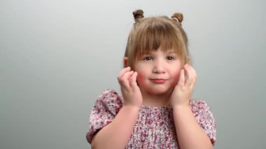 Çocukluk duygularının arka plan videosu, yüzünü kapatıp gülümseyen bir kızın portresi. Çocuk saklambaç oynuyor, mutlu bir çocukluk. Yüksek kalite 4k görüntü