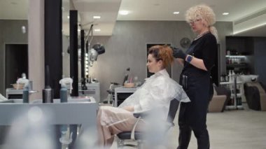 Bir kuaför saç kesiminden önce kadın bir müşterinin saçını çözer. Bir kuaförde resim ve saç kesimi. Yüksek kalite 4k görüntü