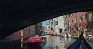 View from a gondola floating on the canals of Venice, Italy. A romantic boat sails along the streets of a romantic city with Mediterranean architecture in a tourist cityscape. High quality 4k footage