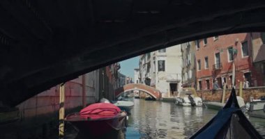Venedik, İtalya 'nın kanallarında yüzen bir gondol görüntüsü. Romantik bir tekne, Akdeniz mimarisi ile turistik bir şehirde romantik bir şehir boyunca yol alır. Yüksek kalite 4k görüntü