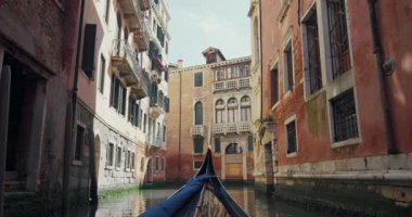 Venedik, İtalya 'nın kanallarında yüzen bir gondol görüntüsü. Tekne, Akdeniz 'in kentsel manzarasında güzel mimarisi olan romantik bir şehrin sokaklarında yelken açıyor.. 