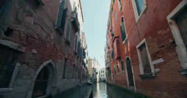 Venedik, İtalya 'nın kanallarında yüzen bir gondol görüntüsü. Güzel evlerin mimarisiyle çevrili romantik şehir manzarasına yelken açan teknenin pruvası. Yüksek kalite 4k görüntü