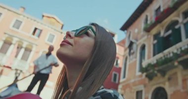 Venedik, İtalya 'nın romantik kanallarında gondolda yüzen bir kızın yakın çekimi. Bir kadın Avrupa 'da bir turistik şehrin mimarisi tarafından büyülenir. Yüksek kalite 4k görüntü