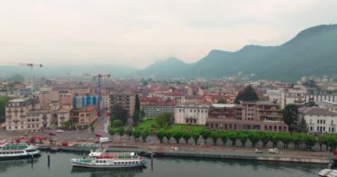 Göl manzarası ve İtalya 'daki Como şehrinin havadan görünüşü. Dağlardaki bir Alp şehrinin kentsel peyzaj mimarisi, yürüyüş için kayıklar sete demirli. Yüksek kalite 4k