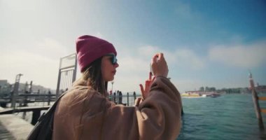 İtalya, Venedik 'te bir kadın telefonla fotoğraf çekiyor. Bir turist hafta sonu için romantizm ve kanallar şehrine seyahat eder. Güzel bir tarihi mimari. Yüksek kalite 4k görüntü