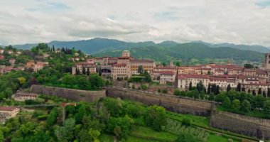 Bergamo, İtalya 'nın yukarısında: Şehirler Tarihi ve Turistik Harikaların Havadan Bakışı, Nefesli Dağ manzarasının ortasındaki zarif Katedral Mimari ve Serene Caddelerini Vurguluyor.