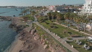 Paphos 'un Havadan Bakış açısı, Kıbrıs Resorts - Havuz, güneşlik yataklı oteller ve Güzel Sahil boyunca uzanan palmiye ağaçları. Yüksek kalite 4k görüntü