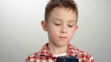 Elinde telefon tutan bir çocuğun portresi. Çocuk oyun oynuyor, mesajlaşıyor ve akıllı telefondan iletişim kuruyor. Yüksek kalite 4k görüntü