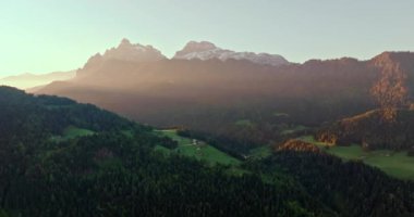 Dolomite Alpleri Günbatımı: Dağ Tepeleri, Yeşil Tarlalar ve Ormanları aydınlatan Güneş Işıkları ile Güzel Günbatımının Hava Manzarası. Yüksek kalite 4k görüntü